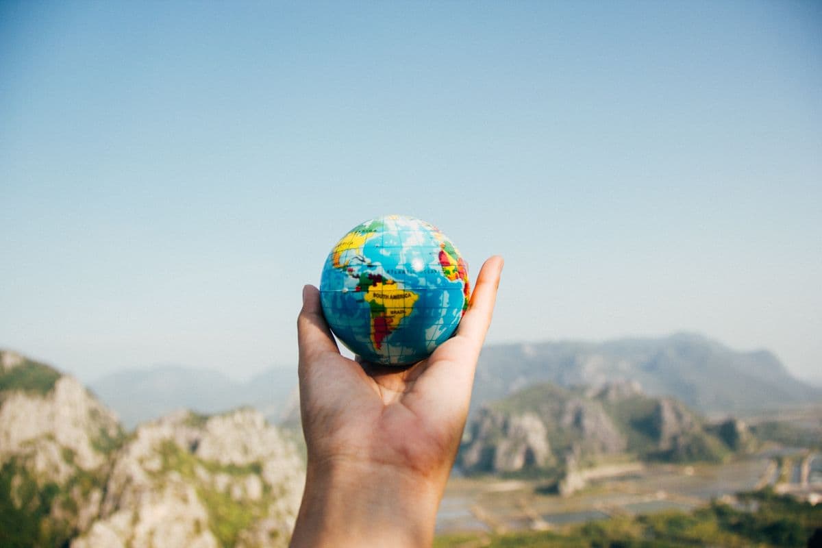 Traveler holding a globe overlooking a mountain landscape